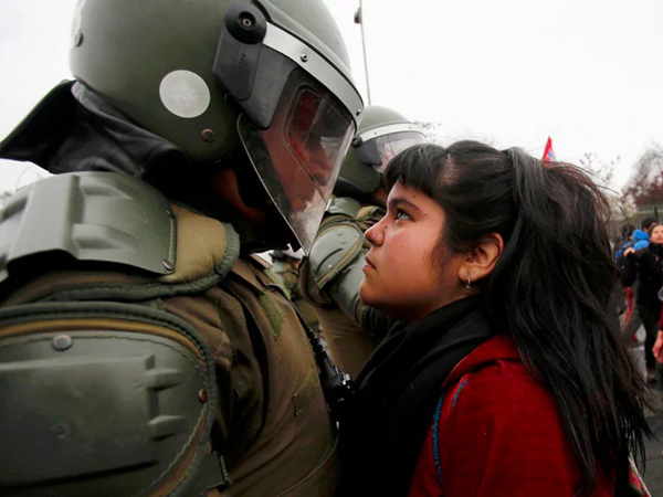The young demonstrator locked eyes with a riot policeman during a pro democracy protest in Santiago, Chile